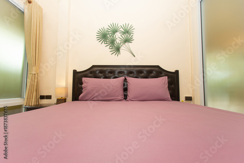 A bedroom with a black bed and pink sheets.
