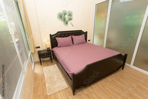 A bedroom with a black bed and pink sheets.