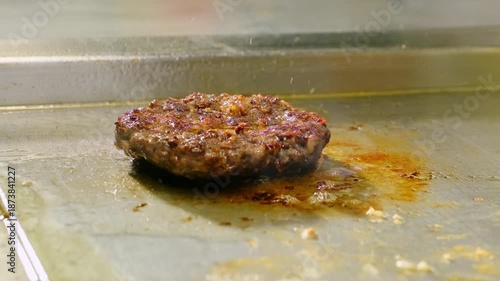 Chef hands insert meat thermometer probe into cutlet frying on grill closeup. Cook master controls burger patty preparation in restaurant kitchen