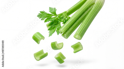 Photos Fresh green celery stalks and chopped pieces artfully arranged and falling against a clean white background, studio shot
