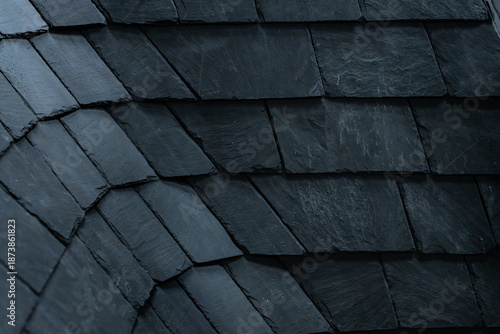Gros plan sur une toiture en ardoise sombre, mettant en valeur la texture naturelle et l’alignement des tuiles dans une couverture traditionnelle.