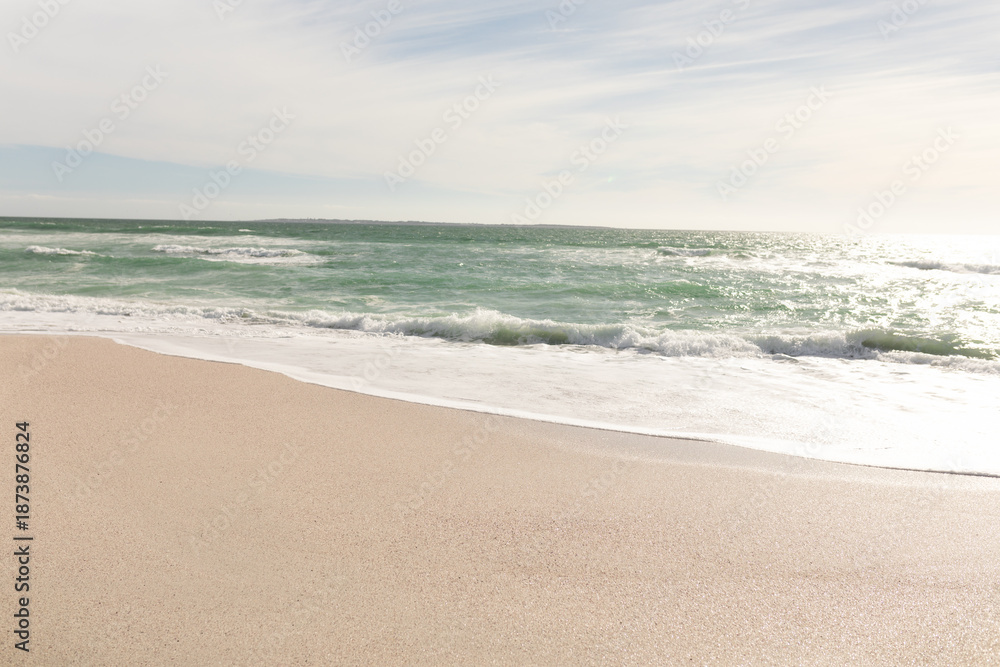 Fototapeta premium Waves in sea crashing on shore at beach against sky during sunny day