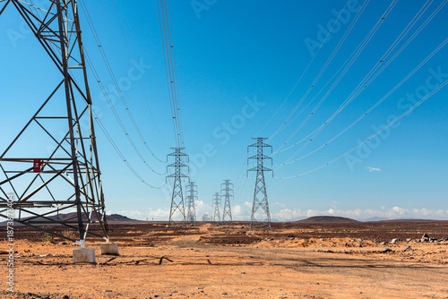 Saudi Arabia desert power lines and transmission towers across open landscape under bright blue sky