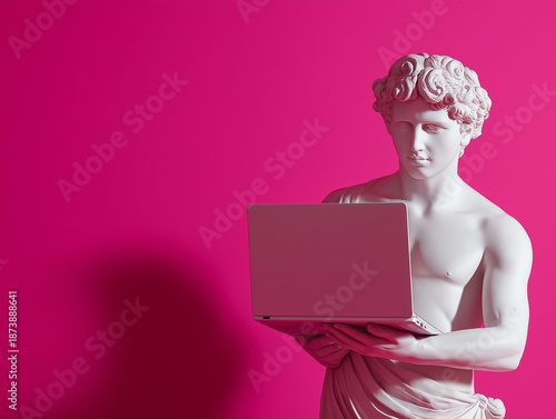 A classical statue of a young man holds a laptop in front of a bold pink background. Digital lifestyle meets timeless art in a modern visual statement.