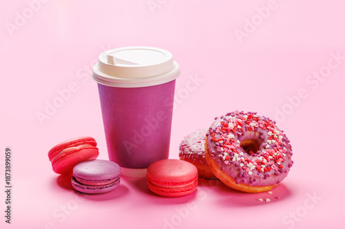 Valokuva A cheerful display of colorful macarons, donuts, and a paper coffee cup on a pas