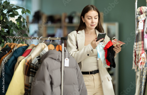 Fotografia Attentive young female customer scanning barcode on panties during shopping in c