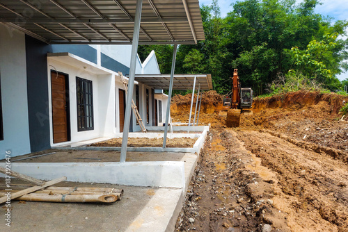 Permanent houses in a row that are still under construction and excavators