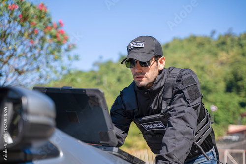 The police officer is working with rugged laptop at the dam.
