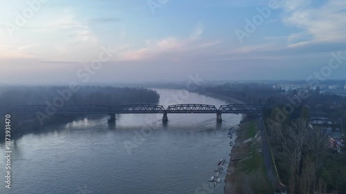 Wallpaper Mural Static aerial view of the historic Ponte di Ferro, showcasing its metallic truss structure as it spans the Po River, winter haze. Torontodigital.ca
