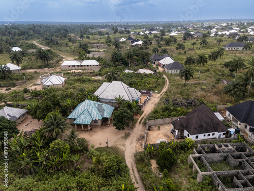 Aerial view of the village nestled among lush greenery, with houses exhibiting diverse roof colors and designs under a cloudy sky, Egbema, Rivers, Nigeria.