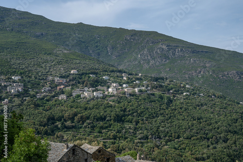 panoramic view village mountainous landscape towards the Gulf of Porto in sunlight with blue skies and spectacular cloud
