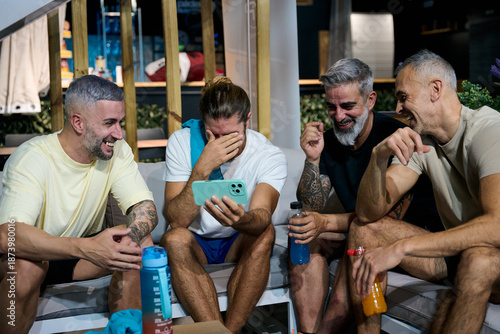 Friends laughing watching smartphone together after paddle tennis match
