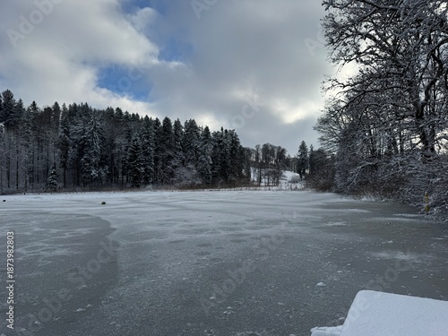 Wide View of a Frozen Lake and Snowy Hills With Blue Sky Breaks