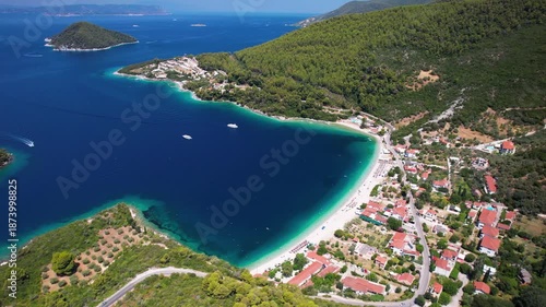 Aerial drone cinematic view of Panormos Bay on Skopelos island, Greece. Scenic coastal road with cars and opens panoramic view of deep blue sea, lush green hills and Dasia islet