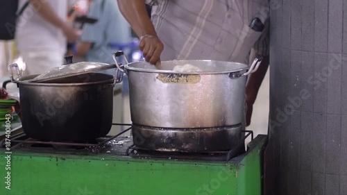 Street vendors are cooking rice while stirring it in a large pan