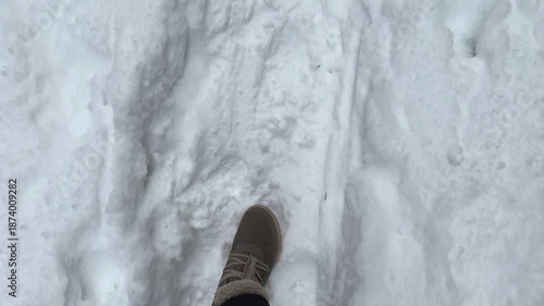 Point of view of foots walking at snowy road at winter. Footsteps in fresh snow showing a continuous stride across a landscape, capturing the movement underfoot in a serene outdoor setting