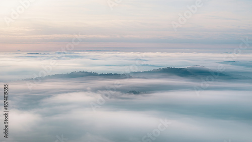 Misty mountains rise above a tranquil sea of clouds at dawn