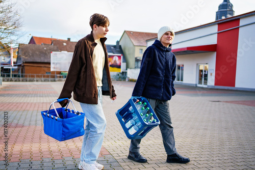 Bild auf Leinwand Two teenager boys, best friends on way to supermarket for shopping and changing mineral water drinks box