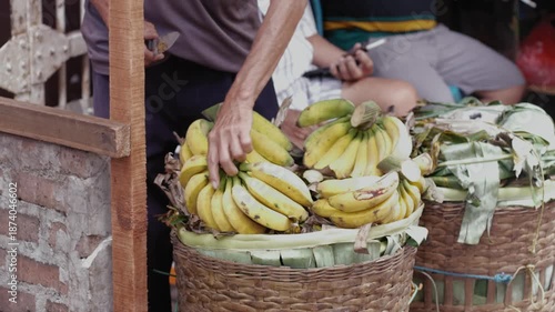 Selective focus of a market vendor arranging banana in baskets at a fruit stall in traditional market