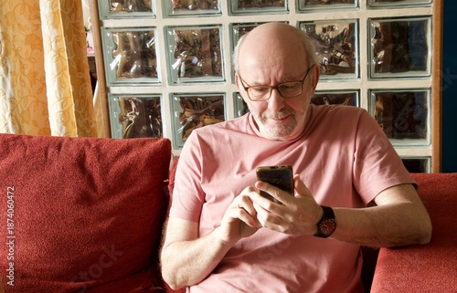 Senior man relaxing on sofa using smartphone