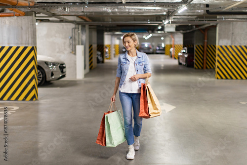 Foto A smiling woman walks through a parking garage carrying shopping bags after a su
