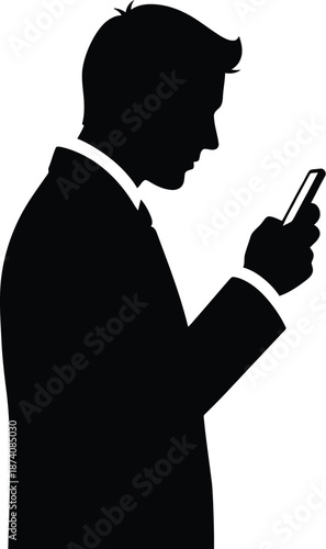Silhouette of a formally dressed businessman standing in profile attentively focused on reading or typing a message on a small mobile smartphone device