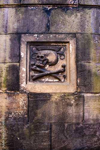 Edinburgh, Scotland: a Memento mori (Latin phrase meaning Remember you must die) representing a stone skull and bones in Greyfriars Kirkyard, the graveyard surrounding Greyfriars Kirk in the Old Town