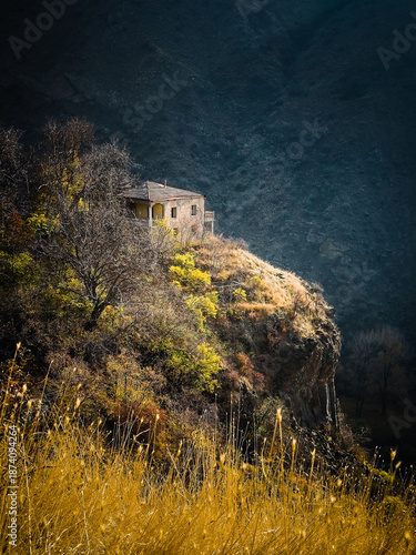 Cottage on grassy edge of mountain against background Tranquil rural scene in picturesque landscape. High quality photo