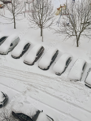 Cars in the parking lot covered with snow. The problem of transport in winter. European winter, cataclysms, snowstorms.