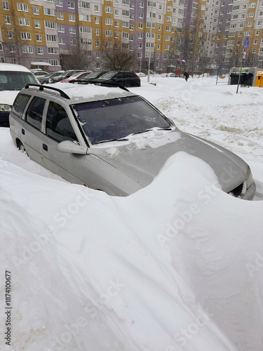 A car is parked in a snowdrift. Heavy snowfall, frost and blizzard in the city. Problem of transport in winter.