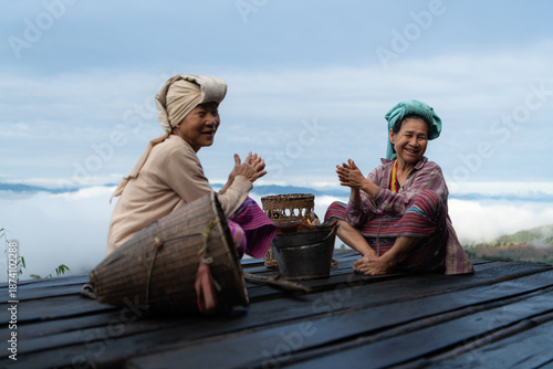 Two Asian rural women sitting together on a wooden platform