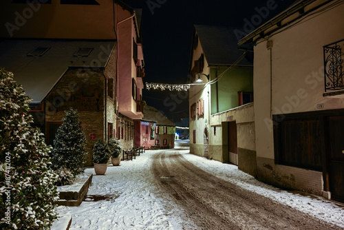 Snowy night street in Arties with festive lights