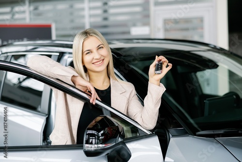 Happy business woman showing car key in dealership