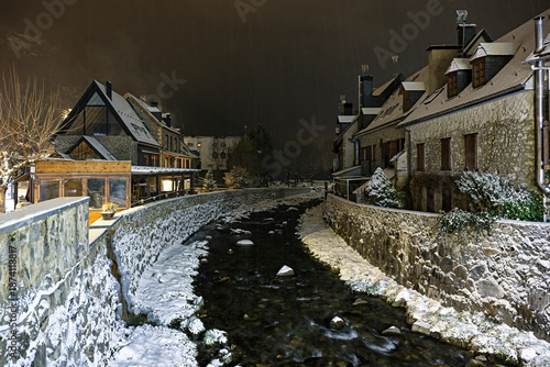 Night view of the Garona River in Arties with snow and mixed architecture