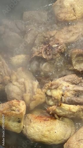 A pan of meat is cooking and the steam is rising. The meat is brown and has a lot of fat