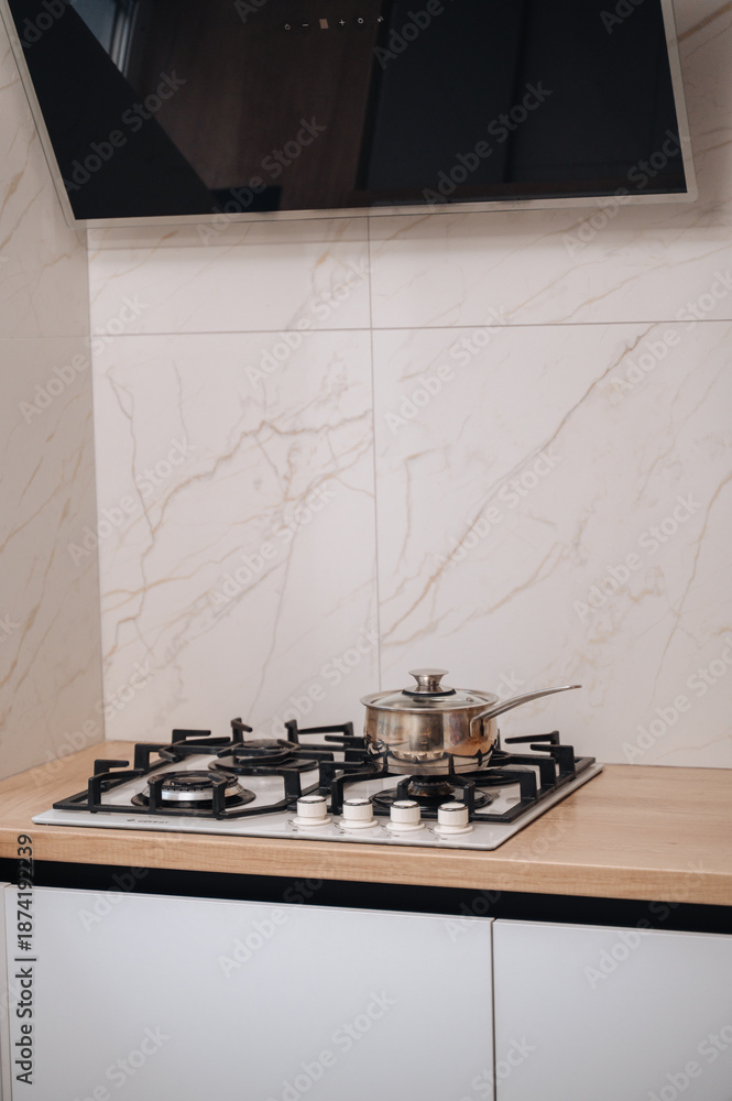 Fototapeta premium Gas stove with range hood in bright modern kitchen interior