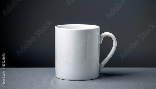 close up of a white ceramic mug with a handle on a grey surface the mug is empty and is placed against a dark grey background