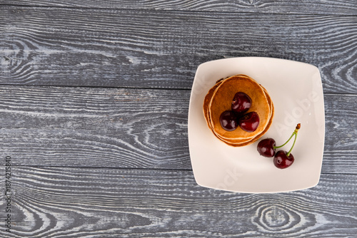 Pancakes with berries on a white plate on the table