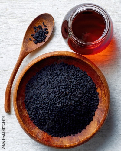 Dark Seeds In Wooden Bowl And Jar Of Oil On White Background