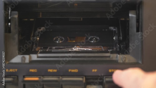 Person pressing play and stop buttons on vintage cassette deck