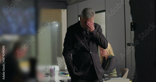 Фотография Worried businessman covering face with hand while walking across office conferen