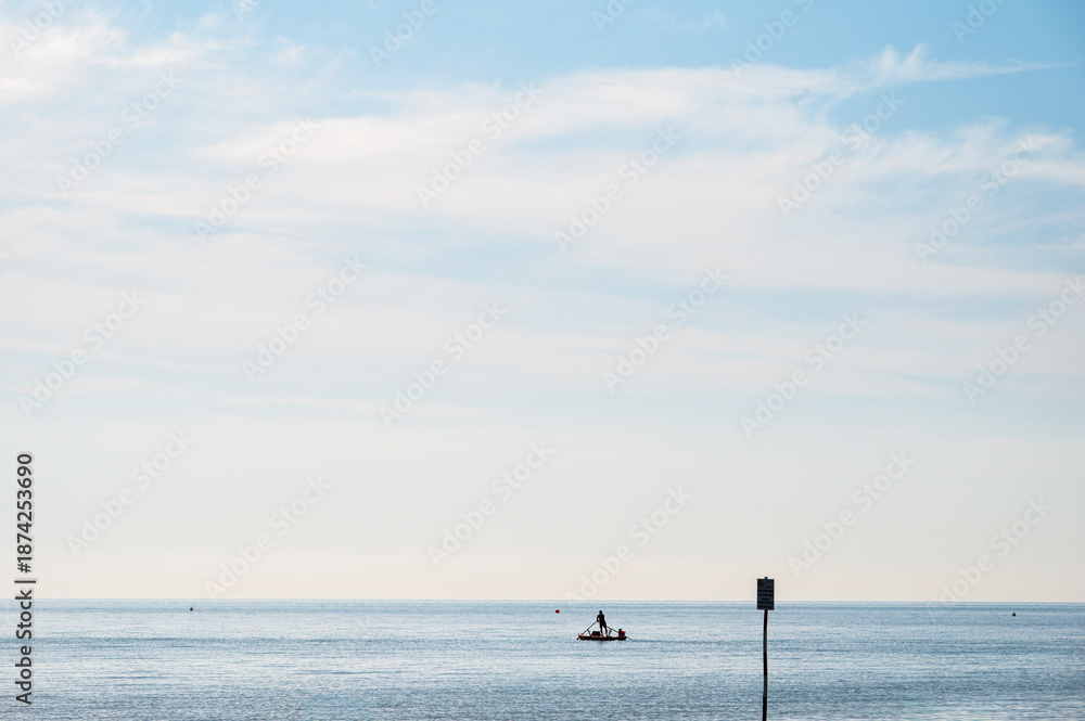 Fototapeta premium people silhouette on a boat in front of a Adriatic Sea beach during a summer day, Bibione Pineda, Venice, Italy