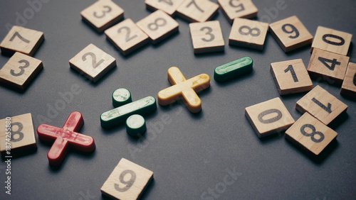 Primary math operation signs with scattered wooden numbers on gray textured surface for educational and problem solving themes