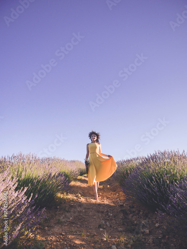Beautiful woman in yellow dress standing with bouquet in lavender field