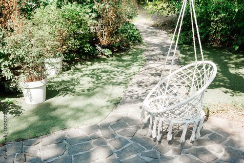 Empty garden path and hanging chair in sunshine