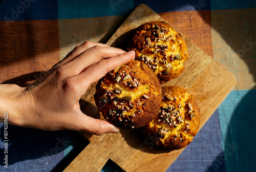 close up of a woman a hand reaching for a freshly baked almond flour roll with seeds. Hands holding fresh bread 
