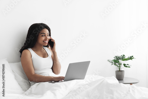 Schilderij op canvas Happy african american woman freelancer talking on mobile phone and using laptop