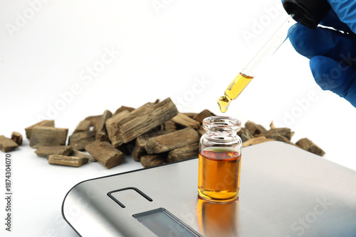 essential oil bottle , chemical beaker ,flask on digital scale white table with blotting paper, and Agarwood ud oil bottle used to blend nice scent smell for perfume and candle by perfumer laboratory