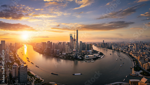 Panoramic aerial view of the Shanghai skyline and river during a golden sunrise.