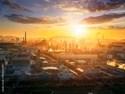 Bilde på lerret Aerial view of a massive industrial factory complex with smoke stacks at sunset under a golden sky